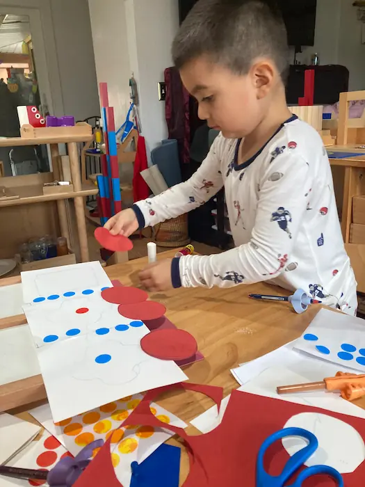 A preschool student using safety scissors and glue for a creative arts and crafts project.