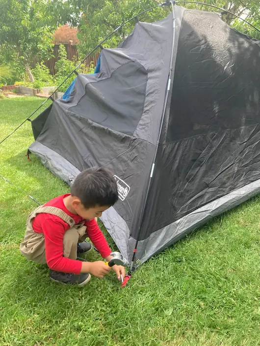 A boy independently assembling a small play tent, developing spatial awareness and self-reliance.