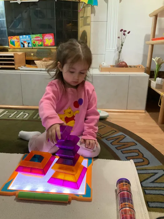 A young girl deeply focused on assembling a wooden educational puzzle, enhancing cognitive and problem-solving skills.