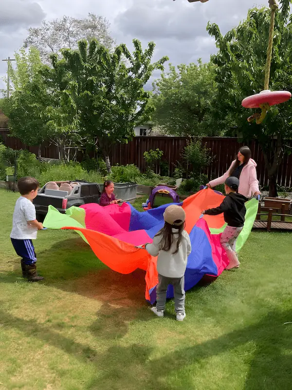 Preschool children working together to build a play tent, practicing teamwork and motor skills.