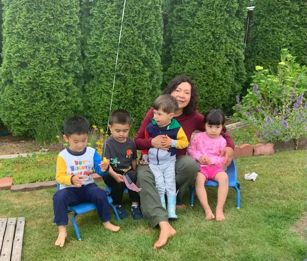 The school director engaging warmly with three toddler students during an interactive classroom activity.